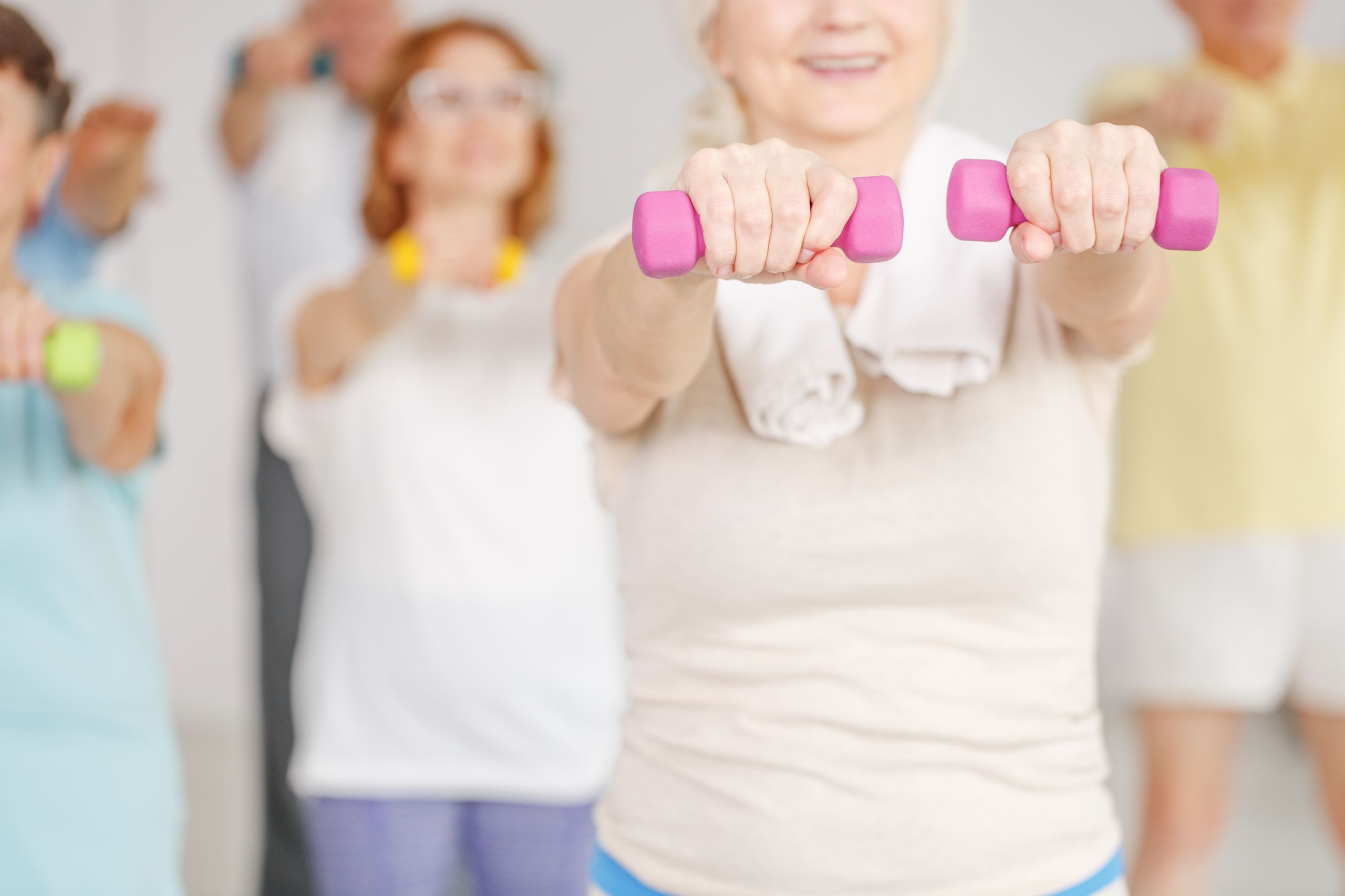 Close-up of older woman exercising shoulders with dumbbells