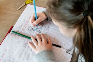 Cute little girl doing homework, coloring pages, writing and painting.